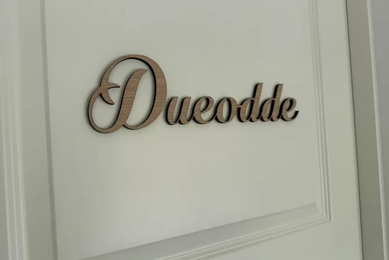 A wooden sign reading 'Dueodde' in italics on the room's white panelled door.
