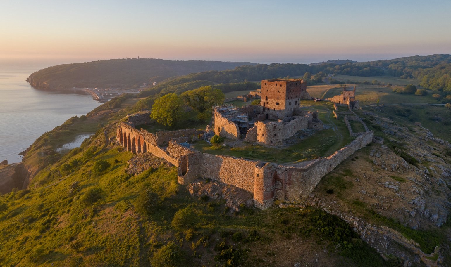 Hammershus — medieval fortress ruins on granite cliffs above the Baltic, in golden-hour light.