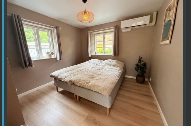 The Opalsøen Room — a warm bedroom with a double bed, an amber pendant lamp, and two garden-facing windows.