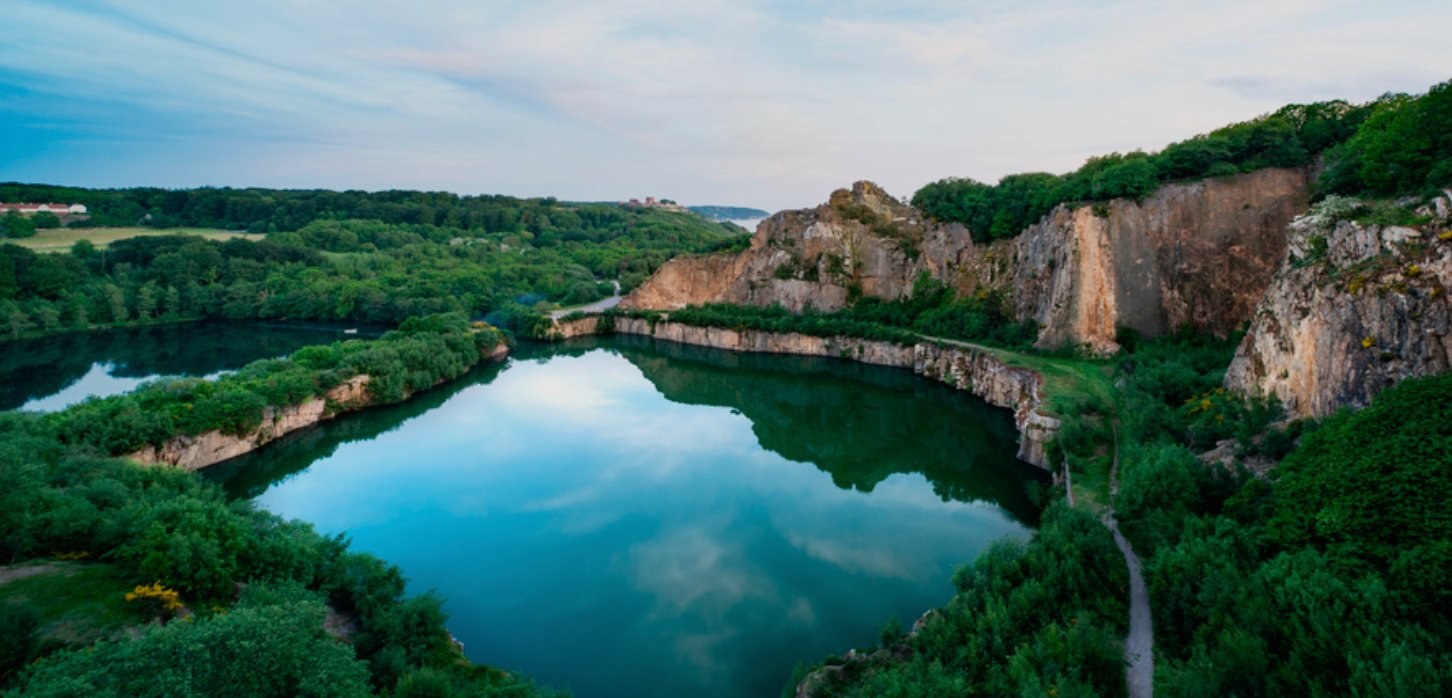 Opalsøen — a turquoise lake in a flooded granite quarry on Bornholm, ringed by steep cliffs and forest.